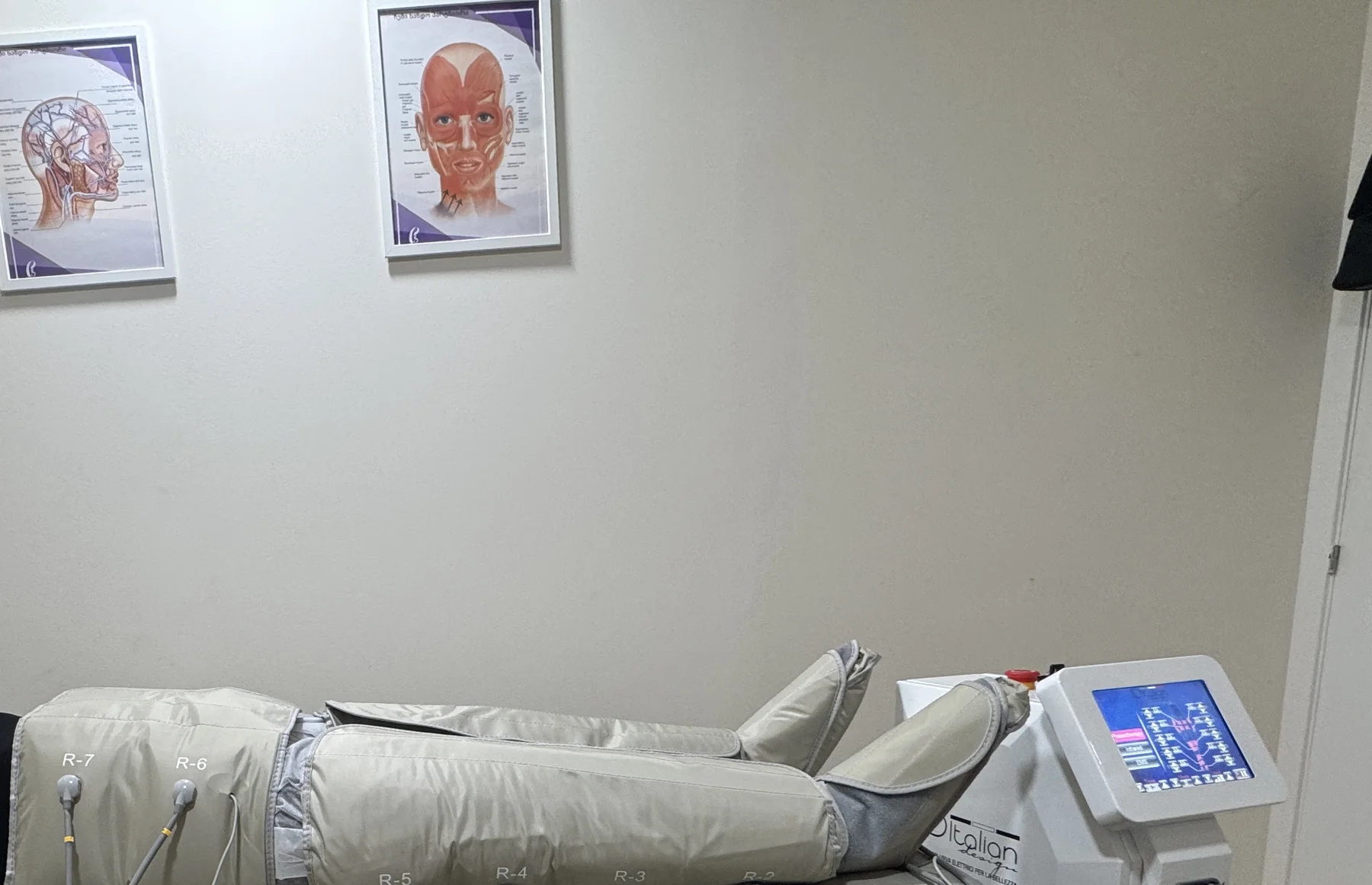 La camilla con el equipo de presoterapia y las láminas anatómicas enmarcadas